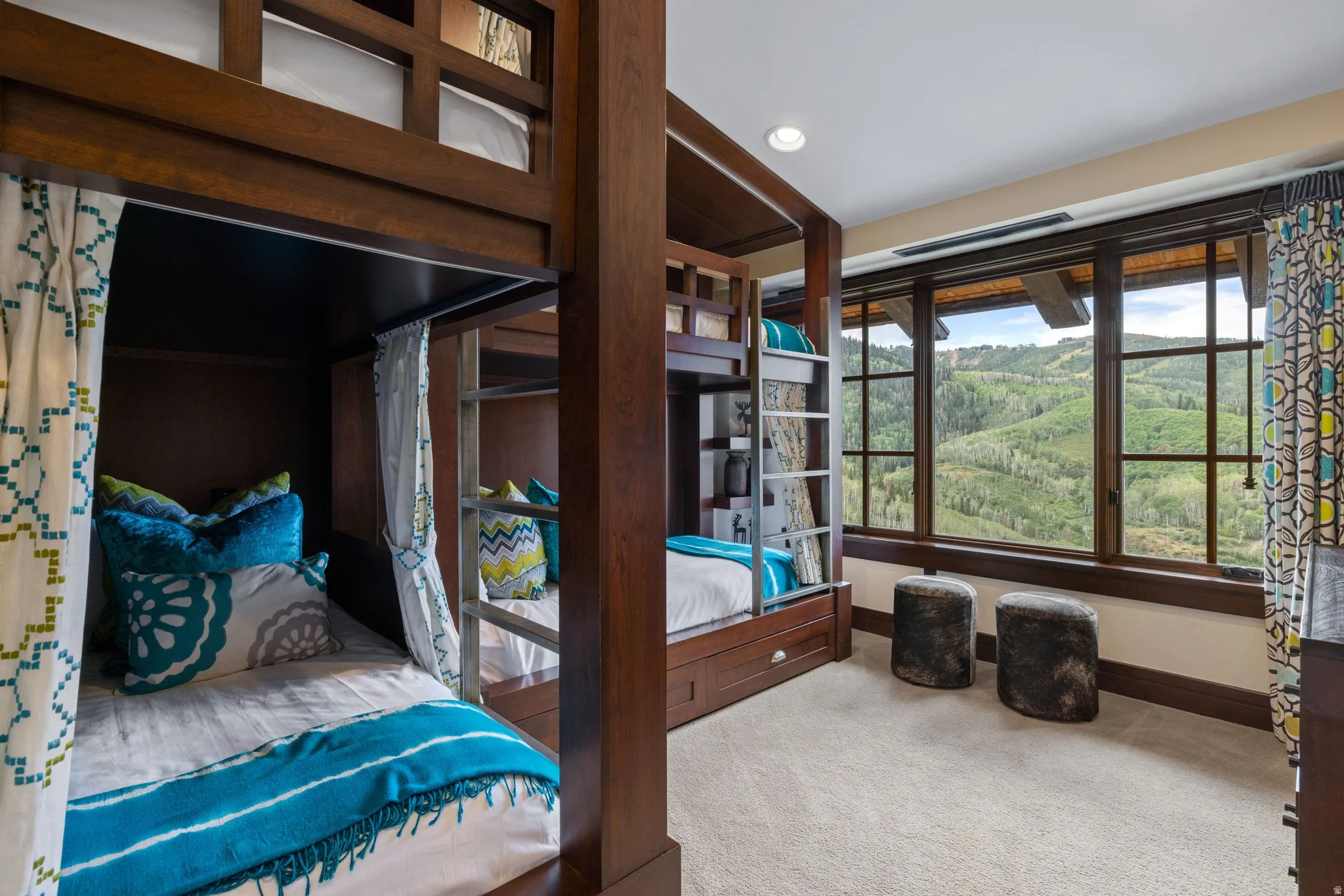 Built-in bunk beds with integrated ladders, large wood-framed windows, recessed lighting, and soft carpeting