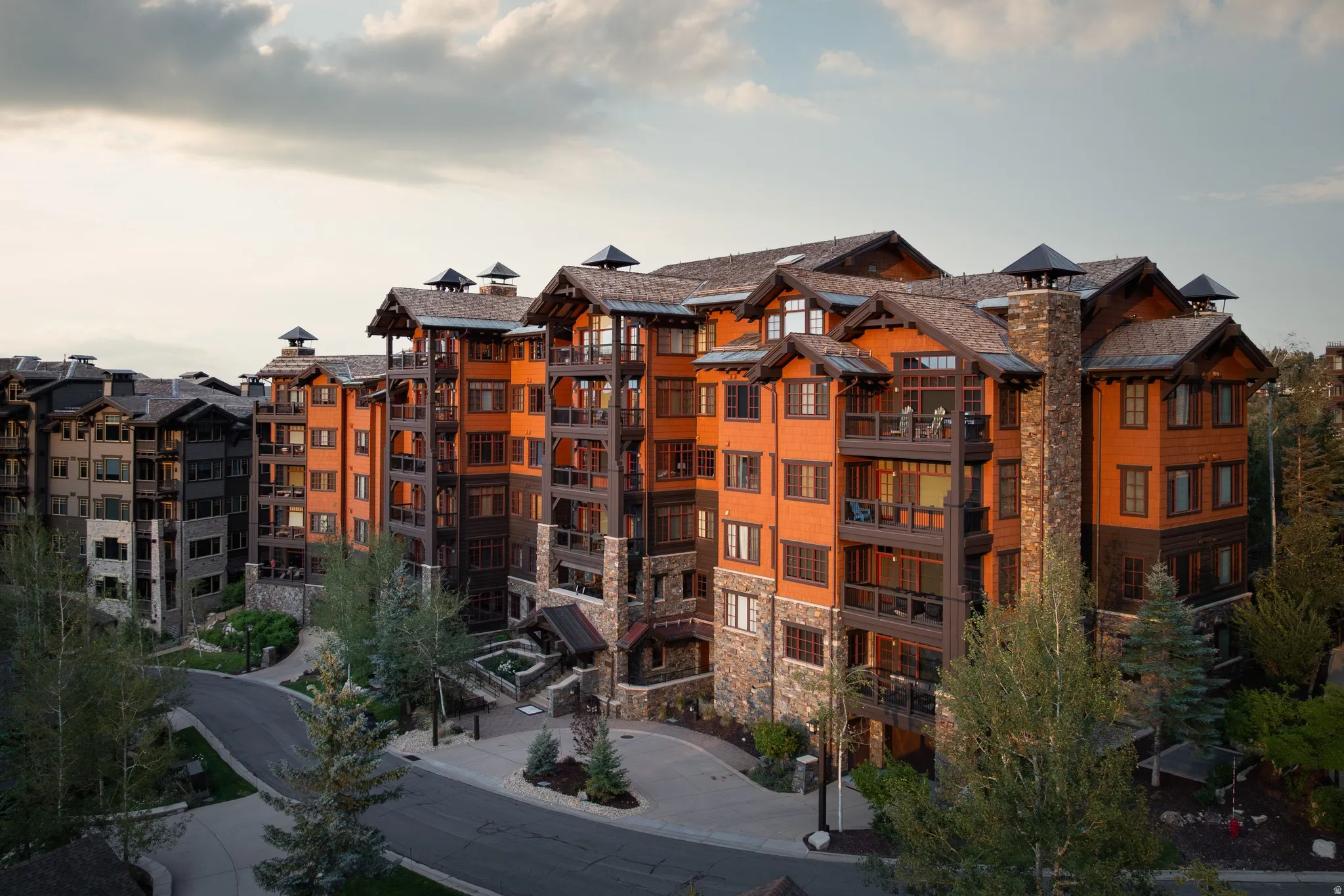 Multi-story residential structure featuring wood and stone facade elements, multiple balconies, and a gabled roofline