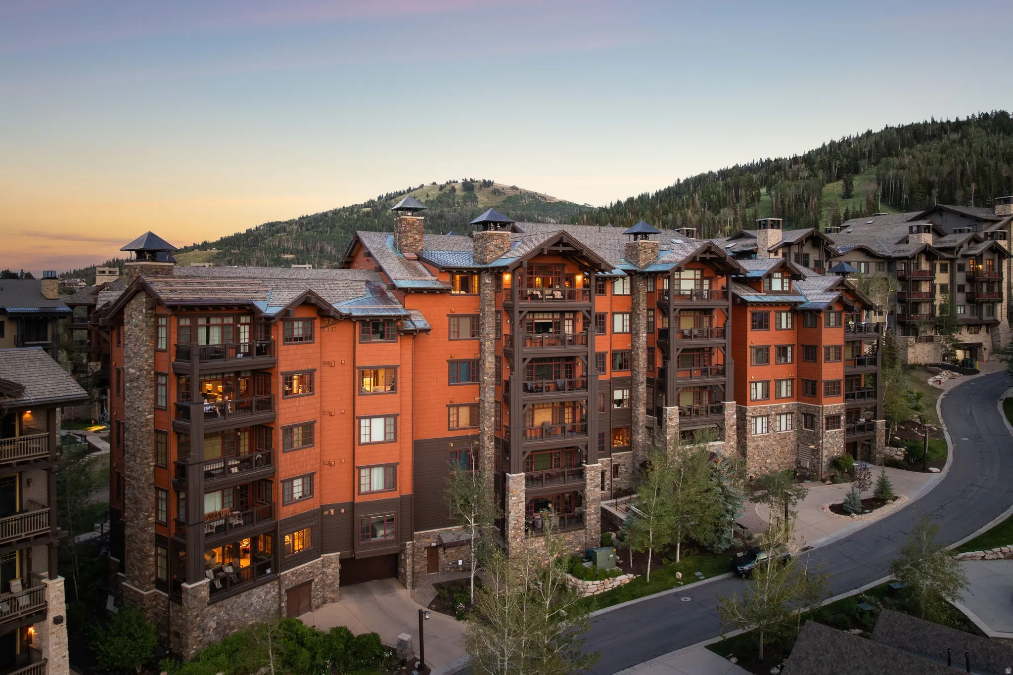 Multi-story property featuring extensive stone detailing, wood-clad siding, and multiple private balconies