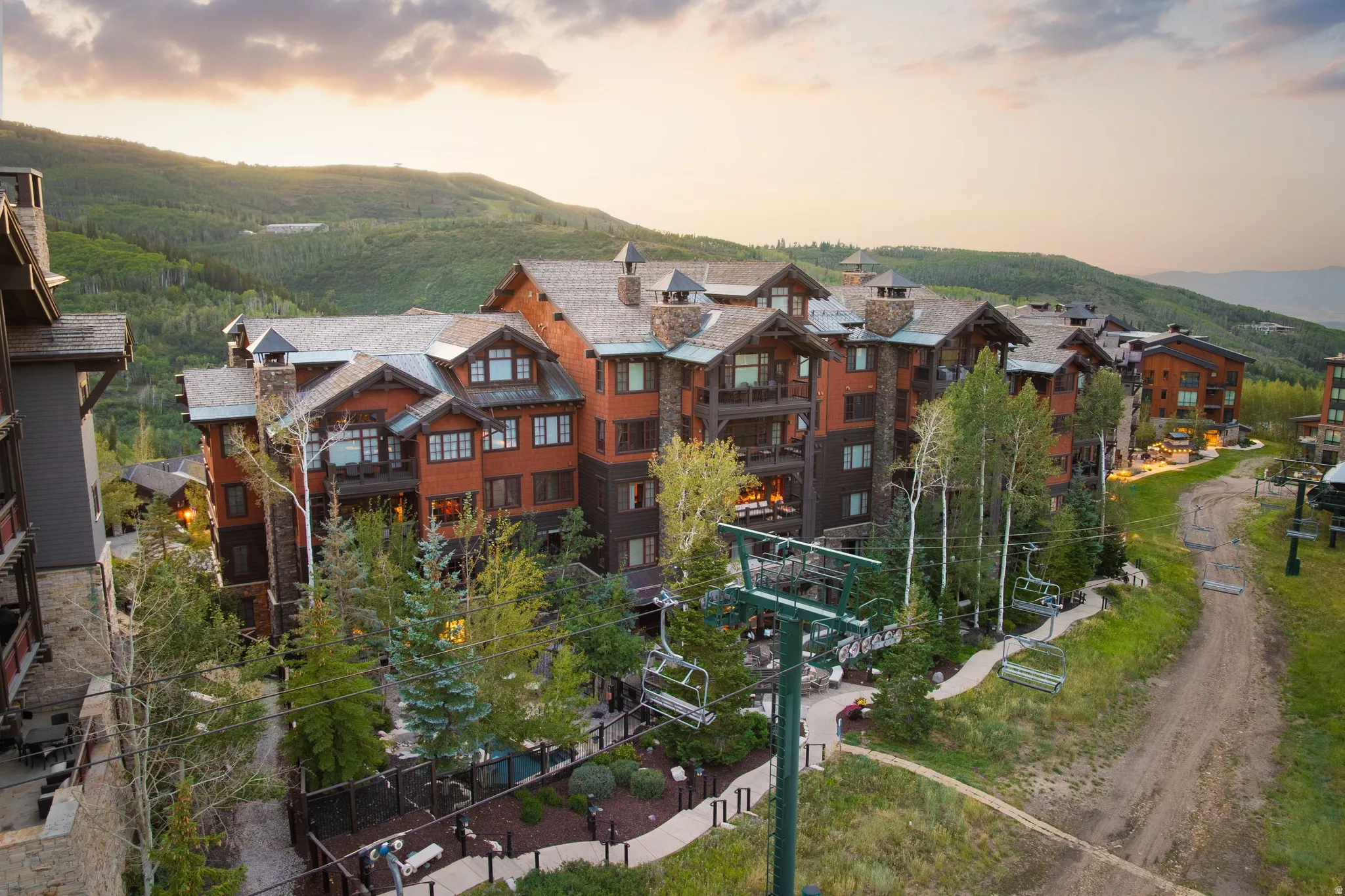 Multi-story building featuring wood siding, stone accents, multiple balconies, and gabled roofs