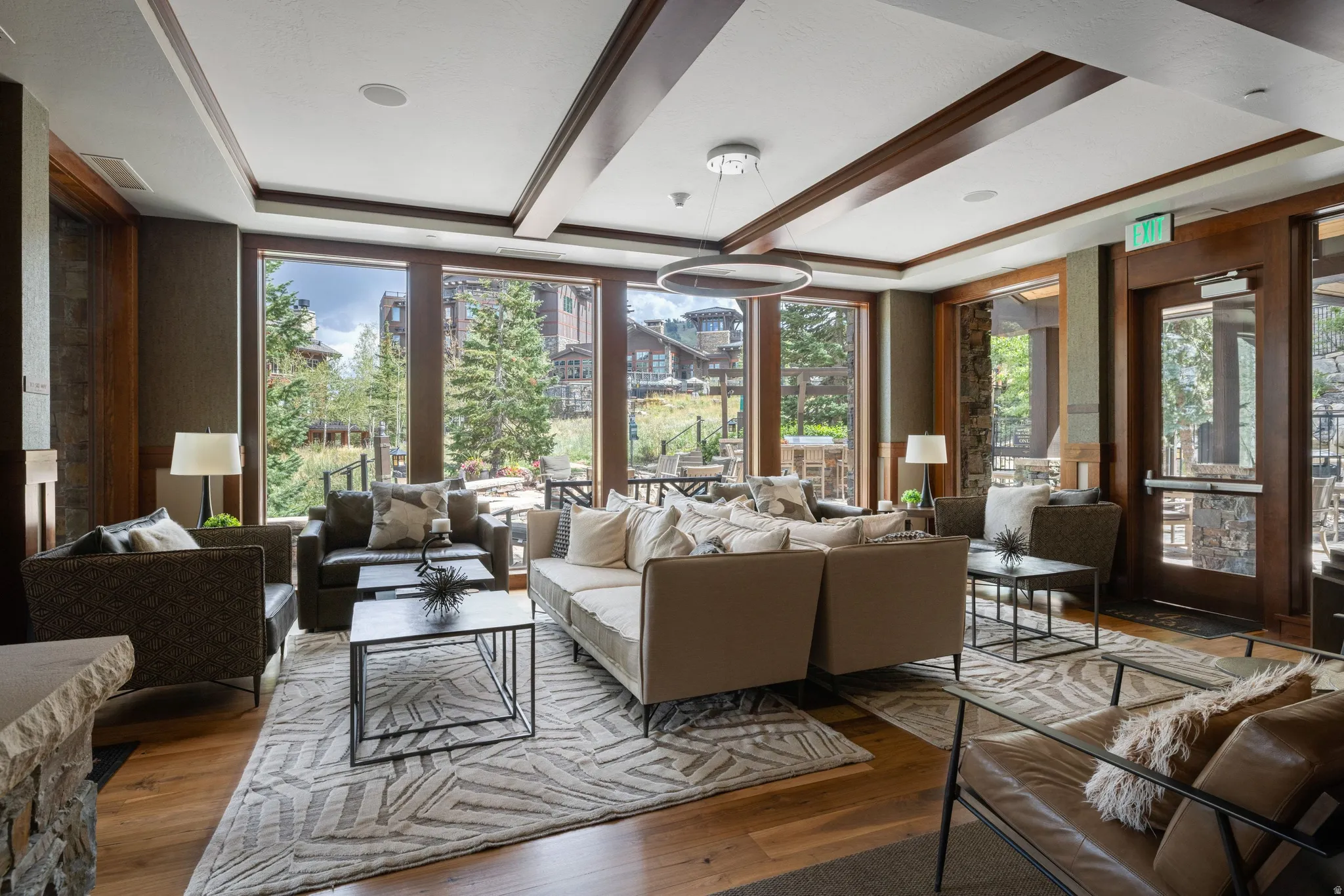 Expansive window wall, coffered ceiling with recessed lighting, wood-finish flooring, and a glass-paneled entry door