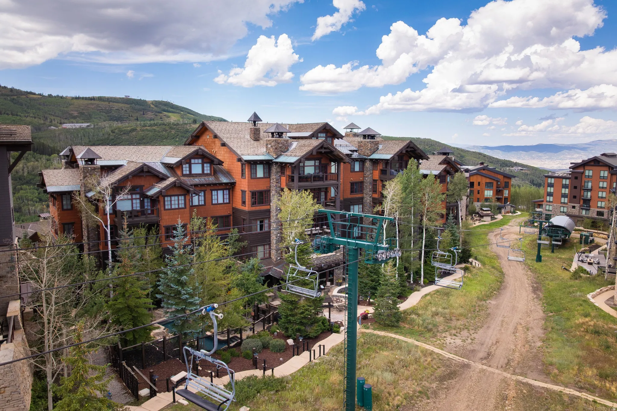 Multi-story building featuring stone and wood siding, multiple balconies, and gabled roofs