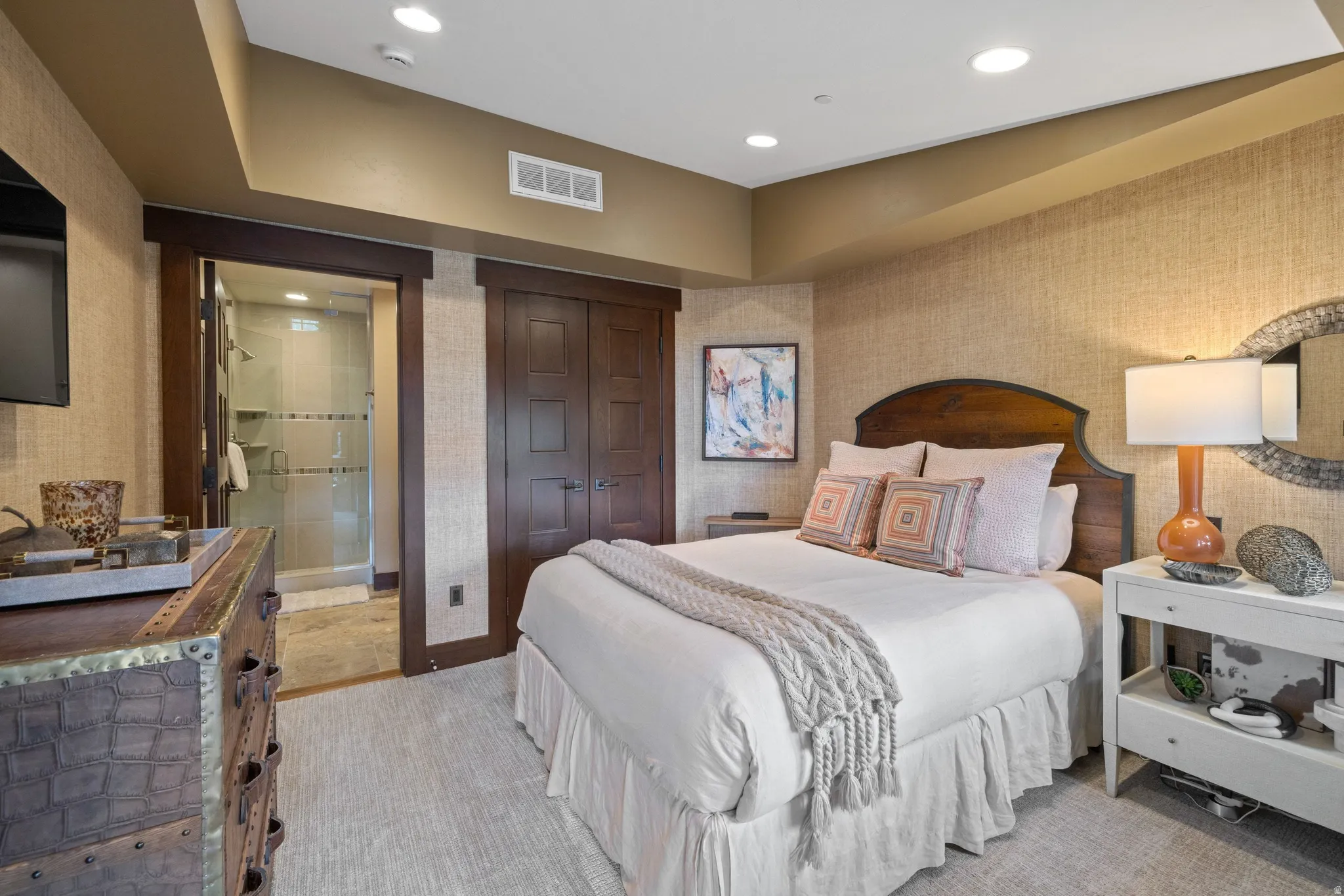 Recessed ceiling lighting, textured wall coverings, wood-finish headboard, wood-finish interior doors, and a glass-enclosed shower