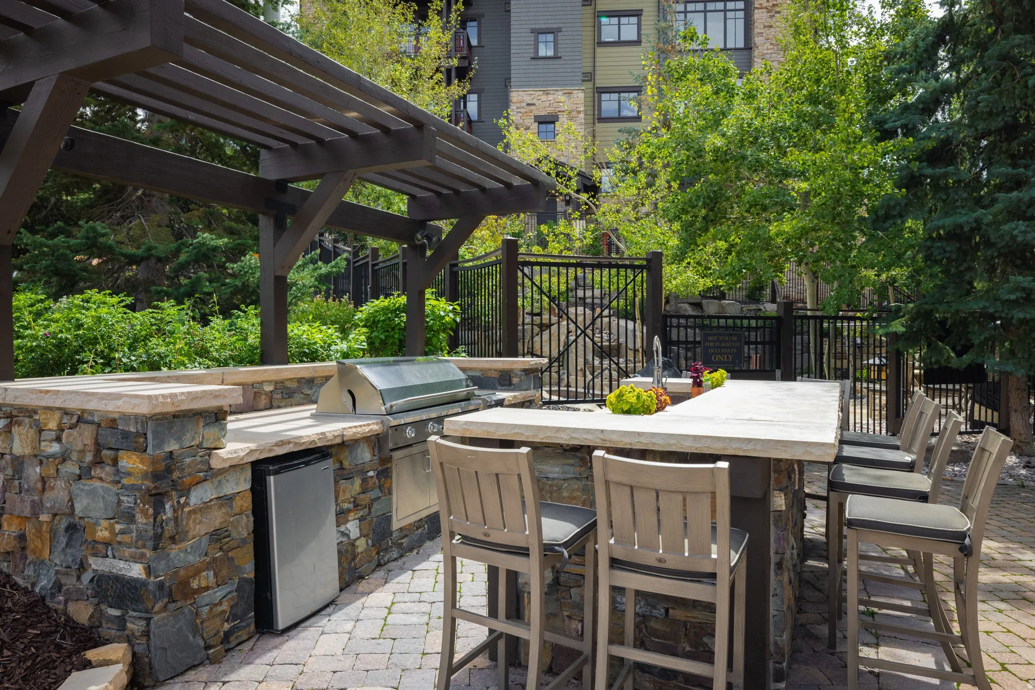 Outdoor kitchen featuring a built-in grill, stone island with integrated sink, and an outdoor refrigerator