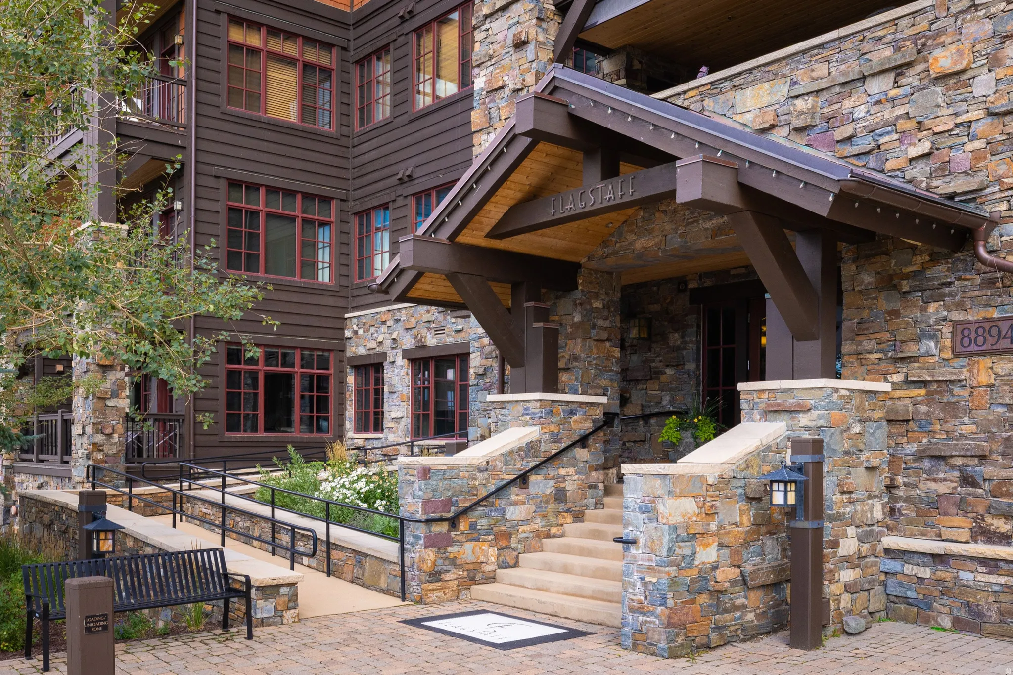 Stone and wood siding exterior with a covered entry, stone steps, and a paved walkway