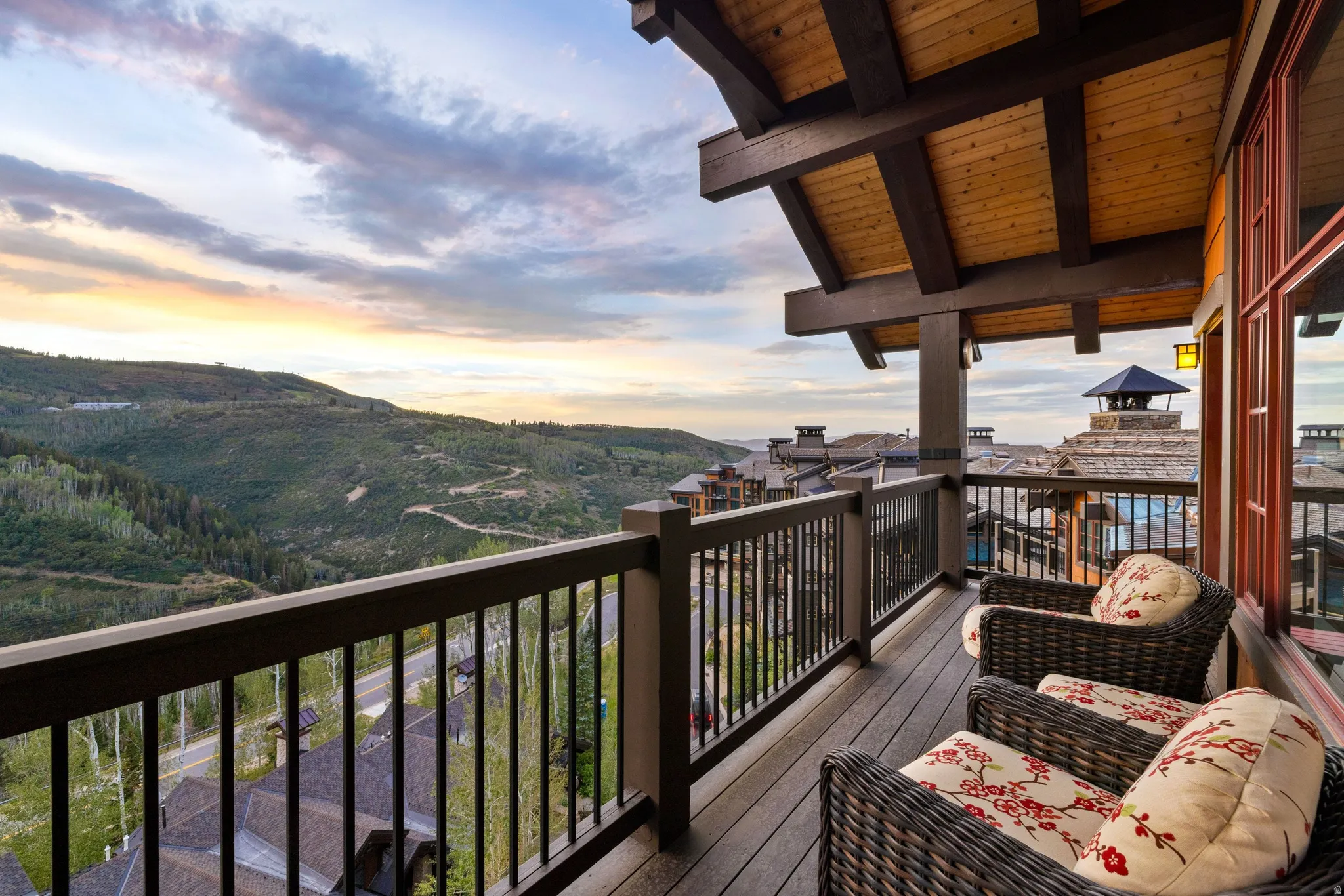 Expansive outdoor deck with wood-finish flooring and sturdy railings, complemented by a natural wood ceiling with exposed beams