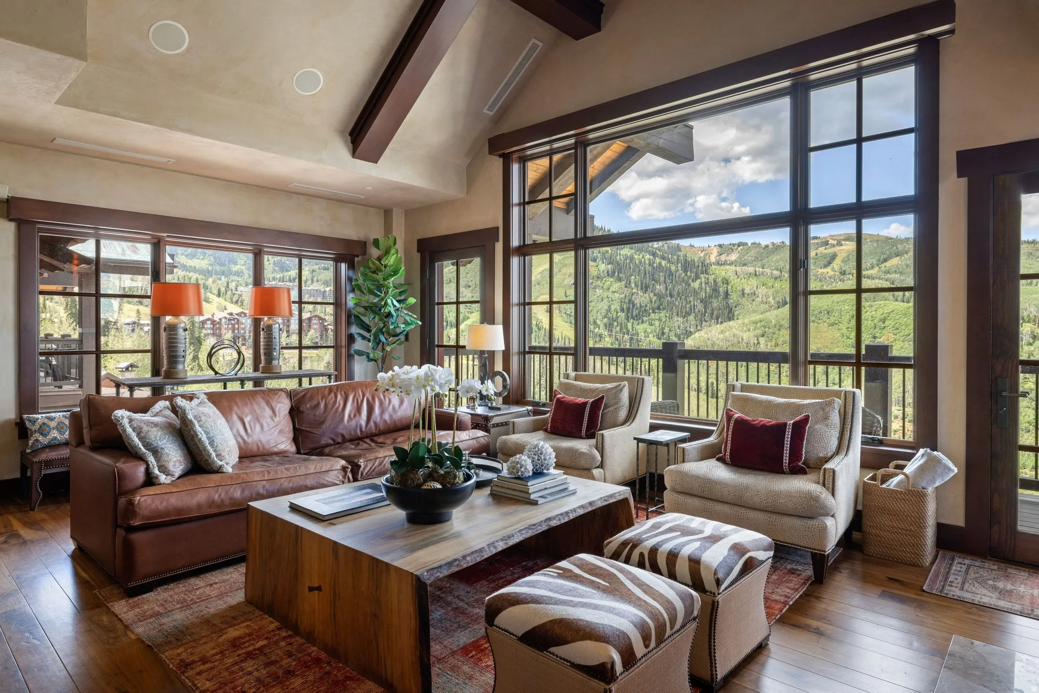 Vaulted ceiling with exposed wood beams, extensive window system, wood-finish flooring, and recessed lighting