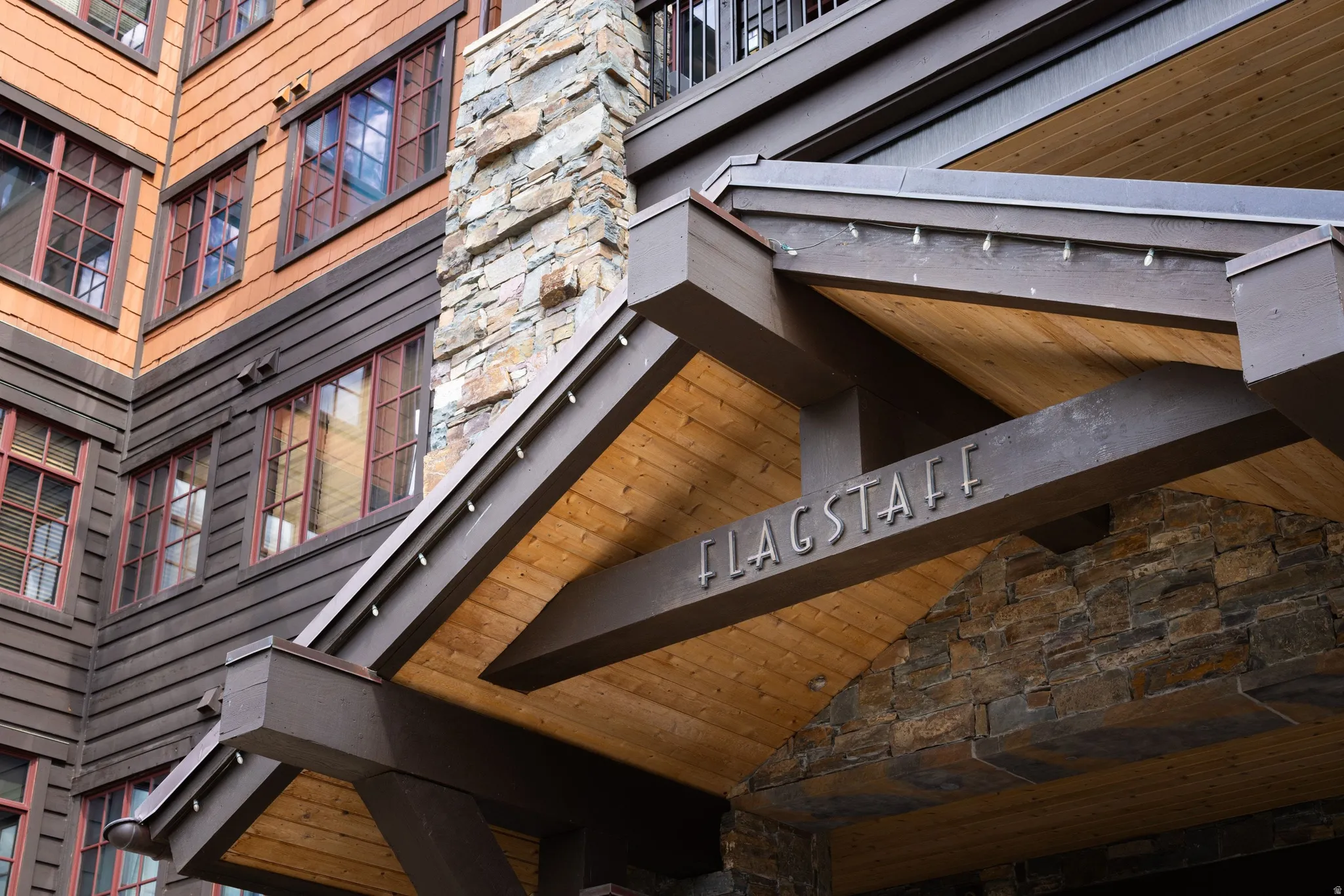 Stone facade with wood beam accents and wood-paneled soffit