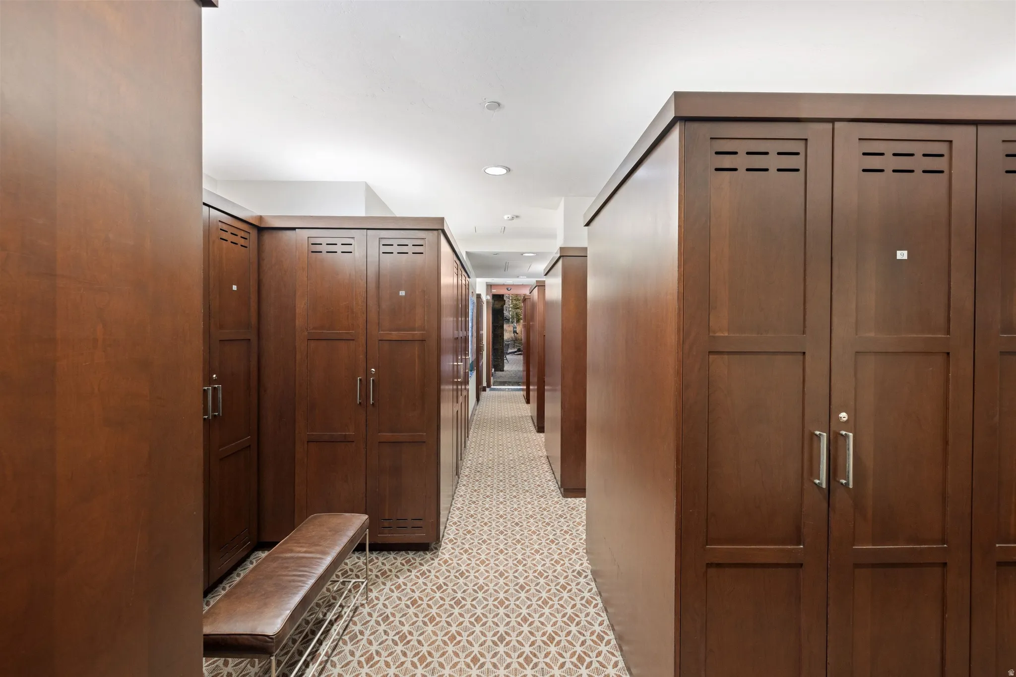 Corridor featuring wood-finish lockers with metal hardware and recessed lighting