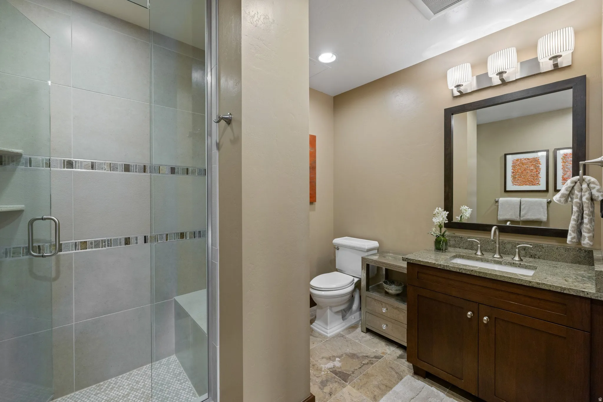 Glass-enclosed shower with tile surround and mosaic accents