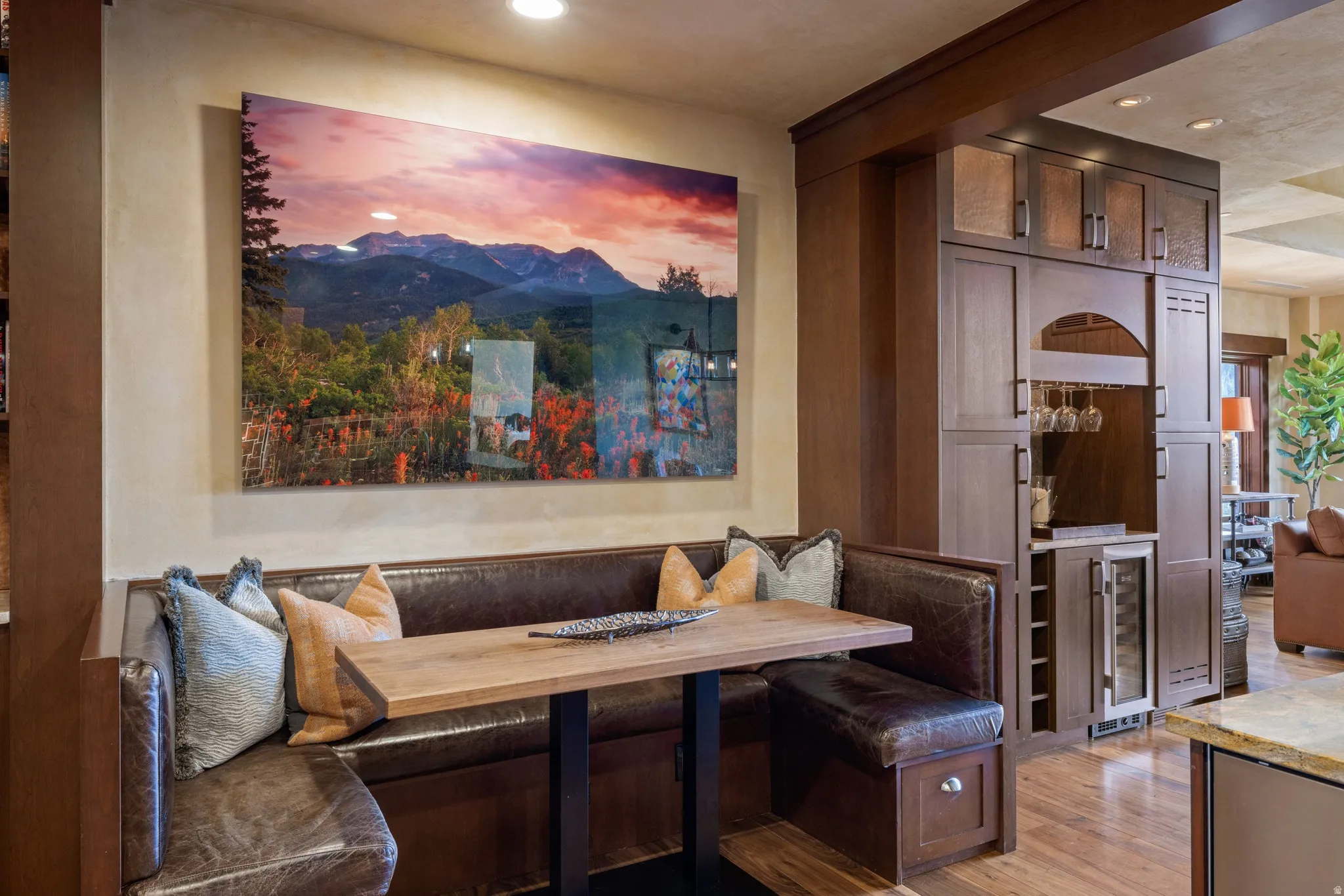 Built-in banquette seating with a wood-finish table, custom beverage center with wine storage, integrated wine refrigerator, and recessed lighting