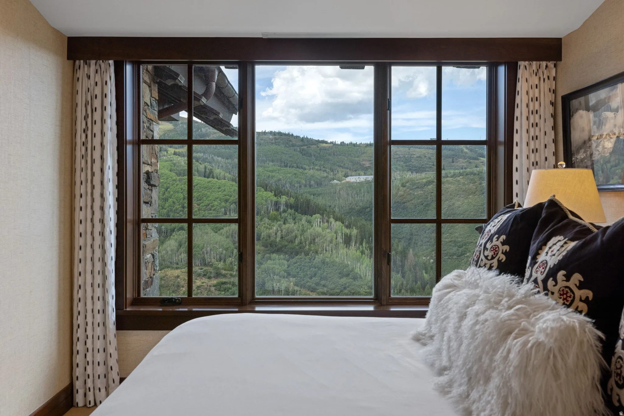 Expansive window wall with dark wood trim, integrated muntin bars, and a stone facade detail