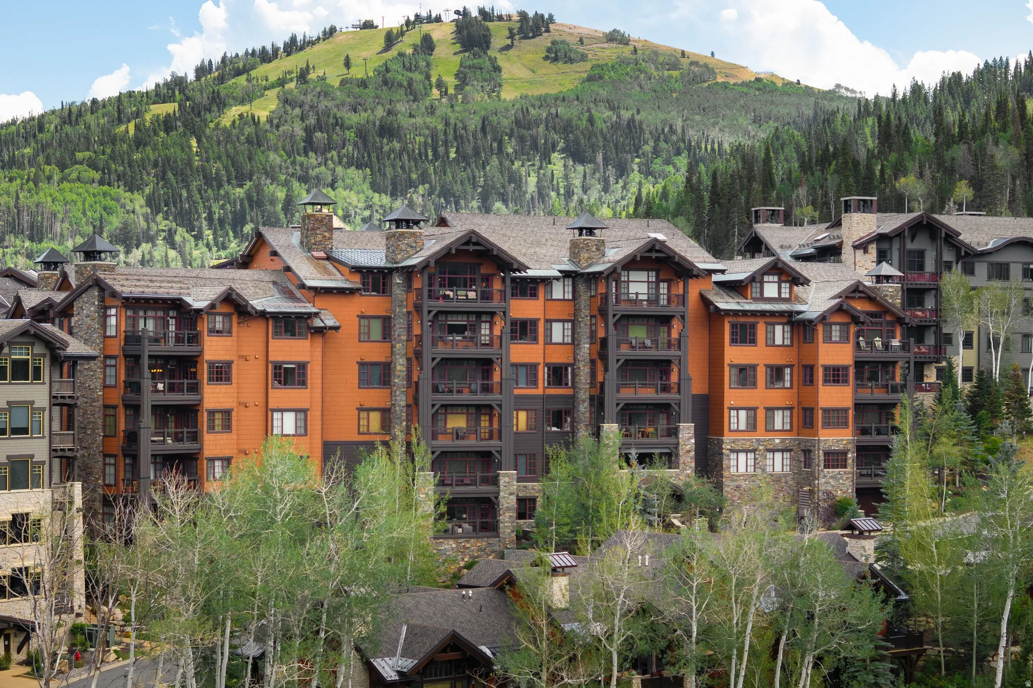 Multi-story building featuring stone and wood siding, multiple balconies, and peaked roofs