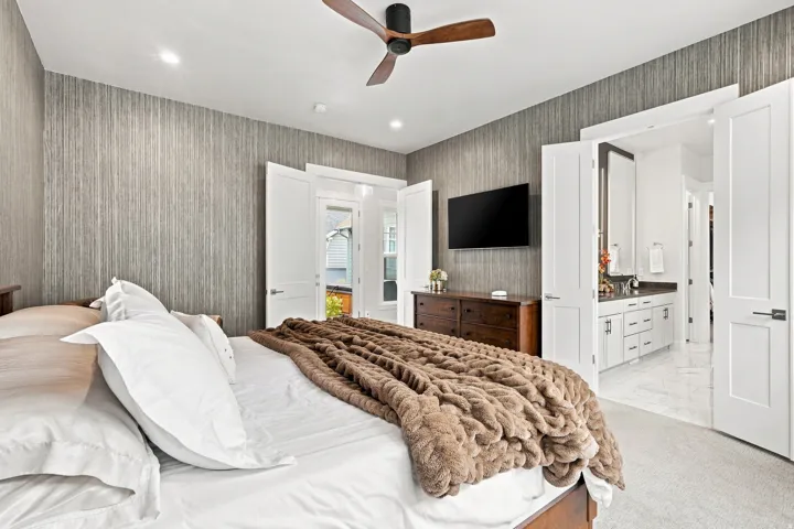Textured wall covering, recessed lighting, ceiling fan with wood-finish blades, white panel doors, and light-toned carpeting
