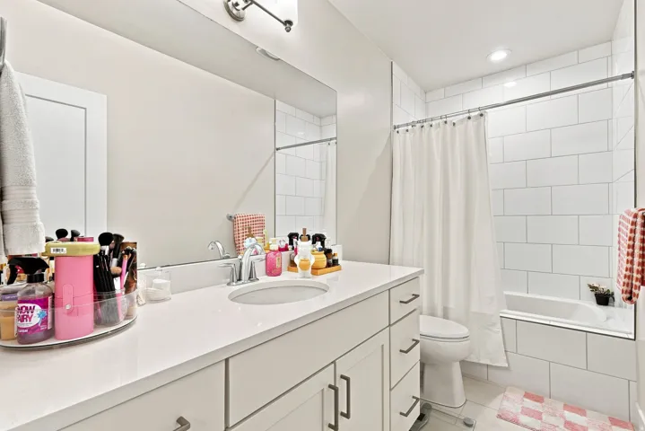 Built-in vanity with a single basin sink, white cabinetry, and a full-width mirror