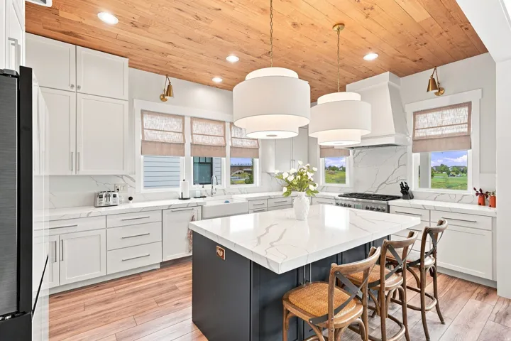 Wood-finish flooring, white cabinetry, a large kitchen island with a stone countertop, a range with a custom hood, and a wood-paneled ceiling