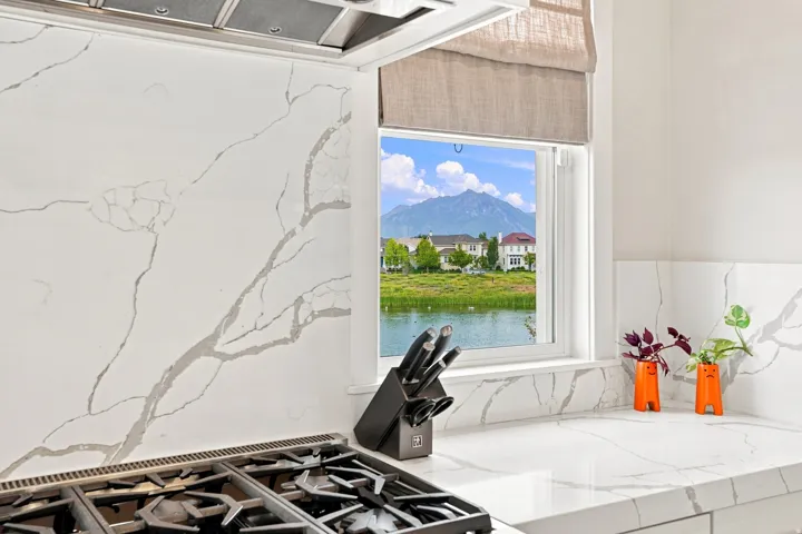 White countertops and backsplash featuring prominent veining, integrated gas range, and stainless steel range hood