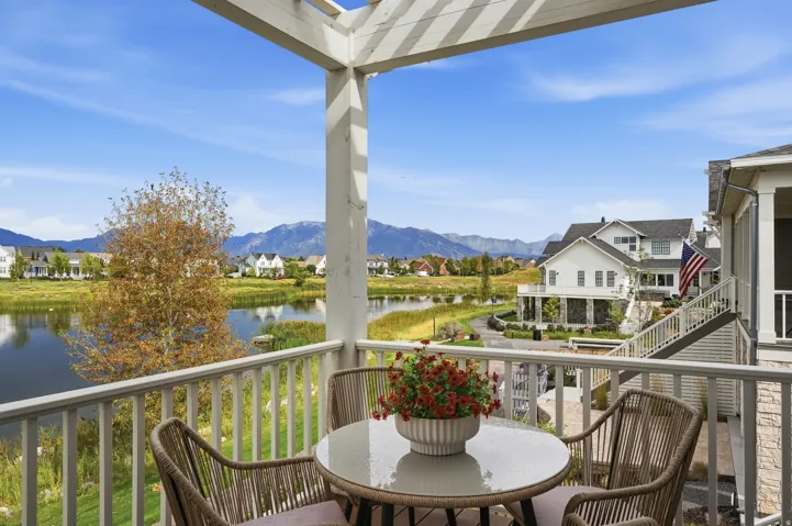 Outdoor balcony with white railing, pergola structure, mountain backdrop, and water feature