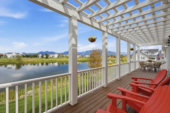 Expansive deck featuring a white open-lattice pergola, composite decking, white railing, and a water body backdrop