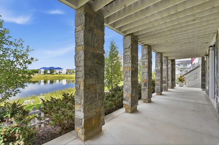 Stone pillars support a covered concrete patio overlooking a natural body of water