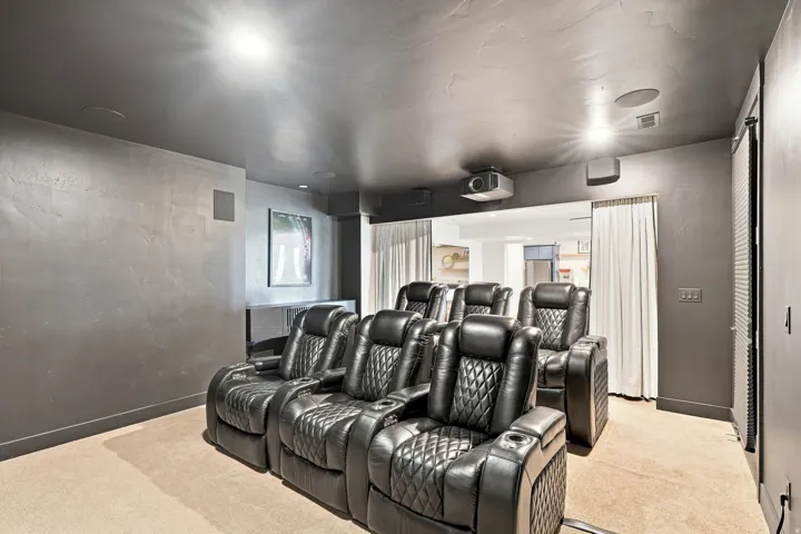 Dedicated media room featuring recessed lighting, a ceiling-mounted projector, and integrated ceiling speakers