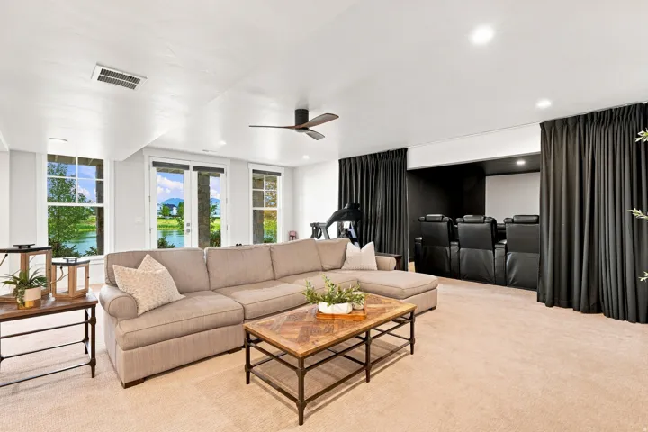 Carpeted living area featuring a ceiling fan, recessed lighting, multiple windows, and a built-in home theater with seating