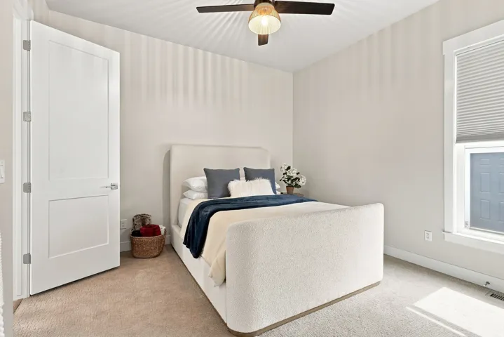 Ceiling fan with integrated lighting, window with a cellular shade, white interior door with paneling, light-toned carpeting