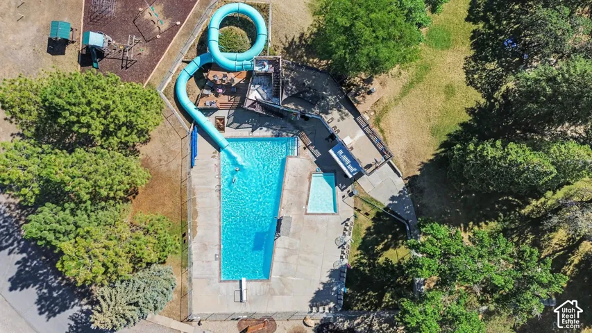 Community outdoor swimming pool with a curved water slide. Next to playground, volleyball pit and pavilion.