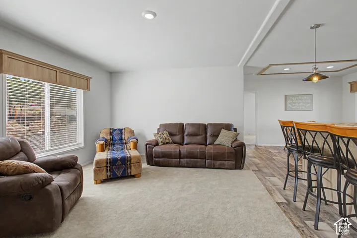 Recessed lighting, window with blinds, wood-finish flooring, accent ceiling detail, and built-in breakfast bar