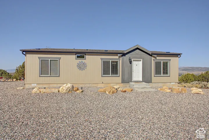 Single-story residence featuring a neutral-toned exterior, an entry porch, and a gravel ground cover