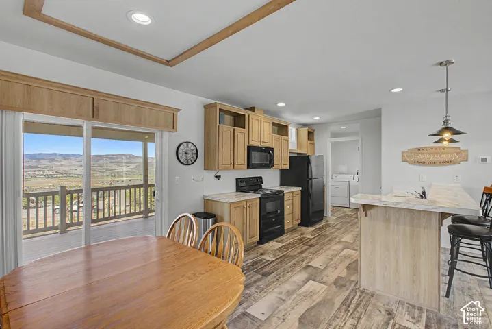 Full kitchen with laminate flooring, light wood cabinetry, off the counter microwave.