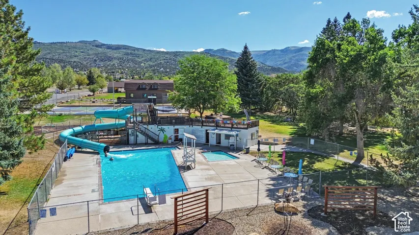 Community outdoor swimming pool with a water slide, a separate spa, and surrounding concrete decking