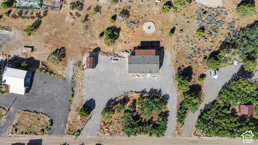 Aerial view of Gravel driveway leading to a single-story dwelling with a gray shingle roof