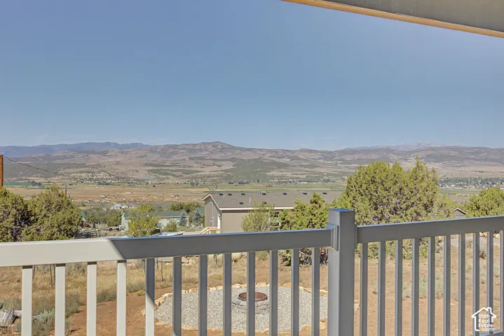 Expansive mountain scenery with a distant valley, and a terraced outdoor area with a gravel fire pit