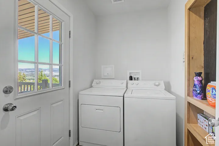 Dedicated laundry area featuring a white washer and dryer, built-in wooden shelving, and a glass-paneled door