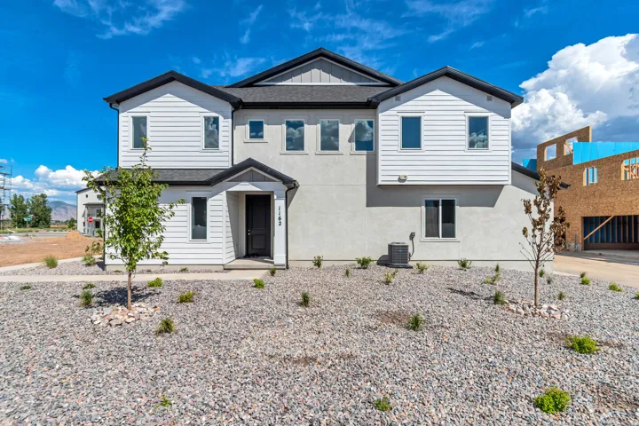 Modern exterior with varied siding textures, covered entry, and black-frame windows