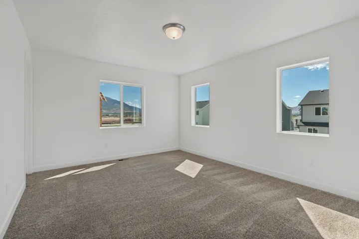 Neutral wall paint, three windows, textured ceiling, flush mount ceiling light, and carpeted flooring
