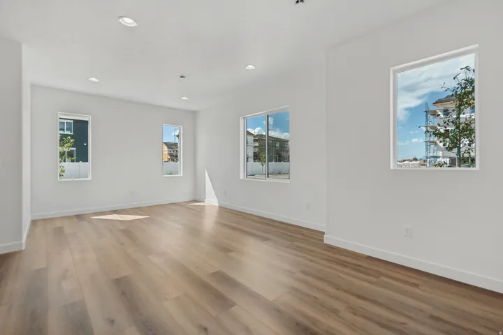 Recessed lighting, light wood-finish flooring, multiple windows, and white walls