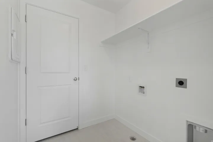 Dedicated laundry area featuring a built-in shelf, neutral wall tones, and wood-finish flooring