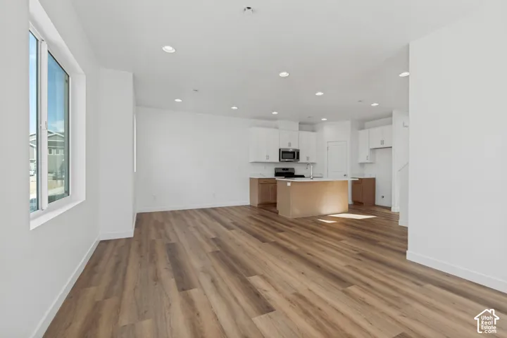 Expansive open-concept living area with wood-finish flooring, recessed lighting, and a large window