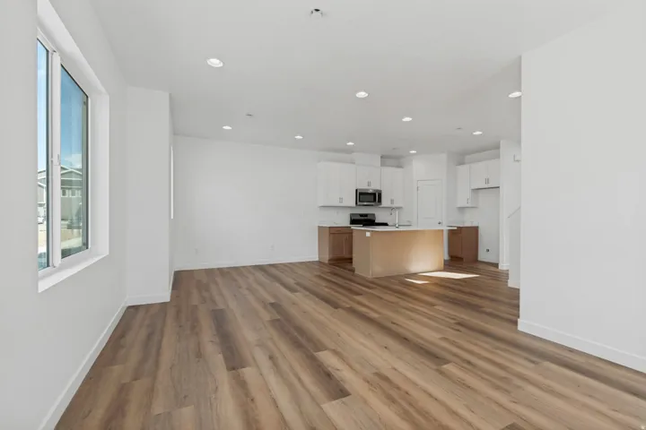 Expansive open-concept living area with wood-finish flooring, recessed lighting, and a large window