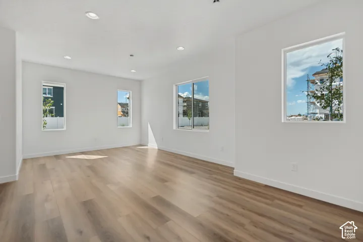 Recessed lighting, light wood-finish flooring, multiple windows, and white walls