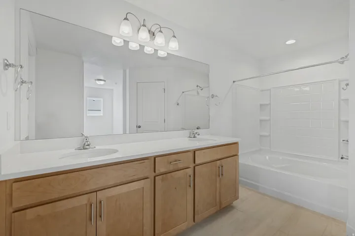 Double vanity with light wood-finish cabinetry and white countertops