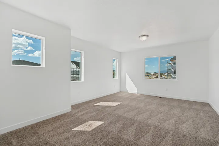 Spacious room featuring multiple windows, neutral paint, a flush mount ceiling light, and patterned carpet flooring