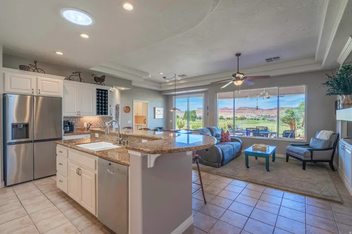 Kitchen island with an undermount sink and stone countertop. Family room with golf course views.