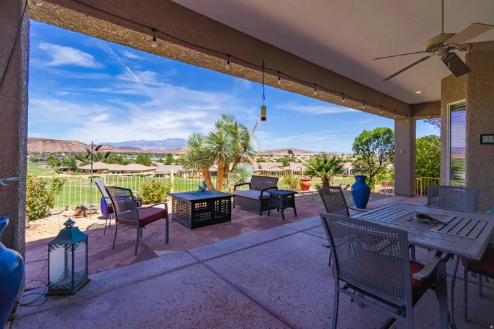 Covered patio featuring a ceiling fan, string lighting, concrete flooring, and an elevated golf course view