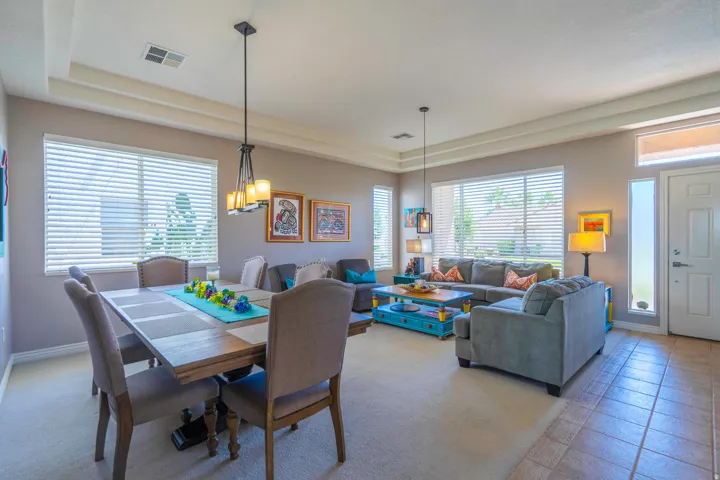 Recessed ceiling with integrated lighting, tiled entry, carpeted living area, large windows with blinds, and a tray ceiling. Formal Dining Room