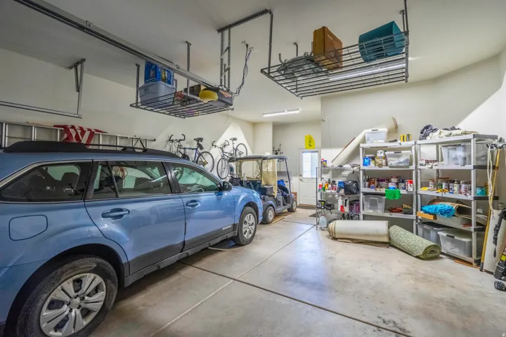 Spacious 2.5 garage featuring  concrete flooring, overhead storage racks, and built-in wall-mounted shelving with multiple tiers for organization and equipment storage
