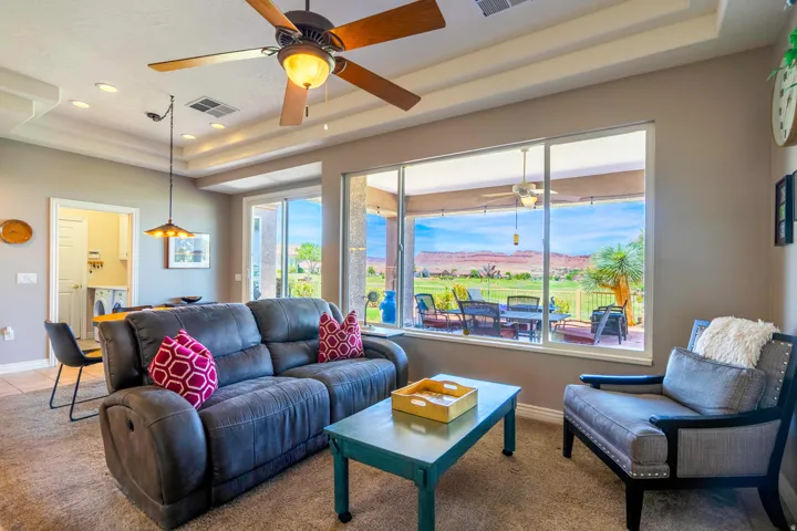 Bright, light-filled family room showcasing expansive multi-panel sliding glass doors framing panoramic golf course vistas