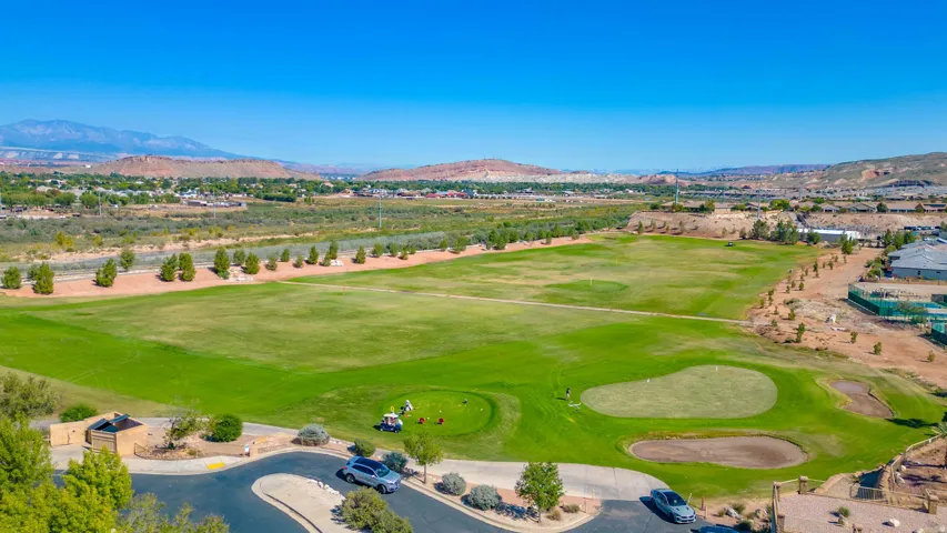 Championship-caliber golf course featuring expansive manicured fairways, multiple bunkers, mature landscaping, water features, and mountain backdrop with clear blue skies